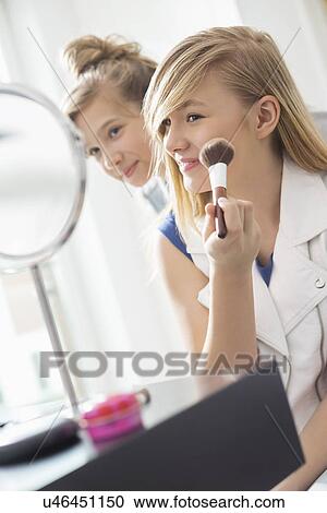 Girl watching sister applying makeup in front of mirror at home View Large Photo Image Stock Image - Girl watching sister applying makeup in front of mirror at home. Fotosearch