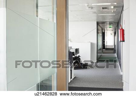 Stock Photo - Glass wall and narrow passageway in office. Fotosearch