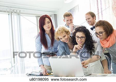 Group of businesspeople using laptop at desk in creative office View Large Photo Image Stock Photography - Group of businesspeople using laptop at desk in creative office. Fotosearch