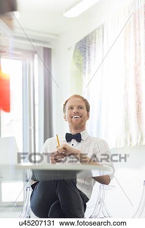 Happy businessman looking away in creative office View Large Photo Image Stock Image - Happy businessman looking away in creative office. Fotosearch