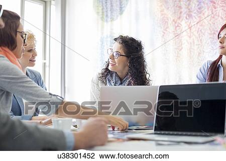 Stock Image - Happy businesspeople discussing during meeting in creative office. Fotosearch