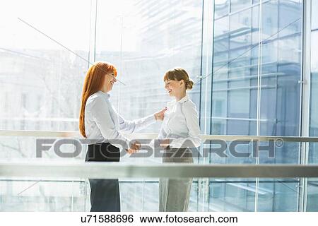 Stock Photograph - Happy businesswomen shaking hands in office. Fotosearch