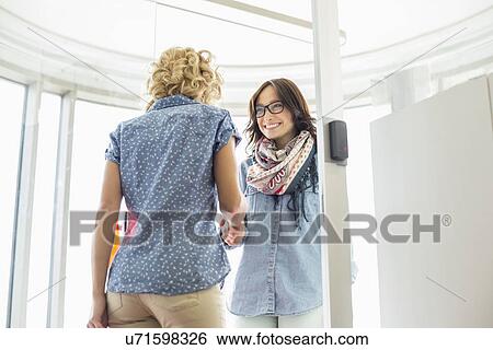 Stock Photograph - Happy businesswomen shaking hands in creative office. Fotosearch