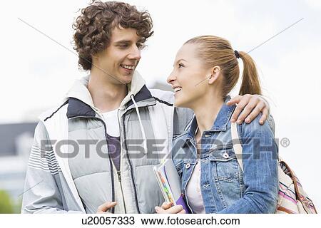 Stock Image - Happy college students looking at each other at campus. Fotosearch