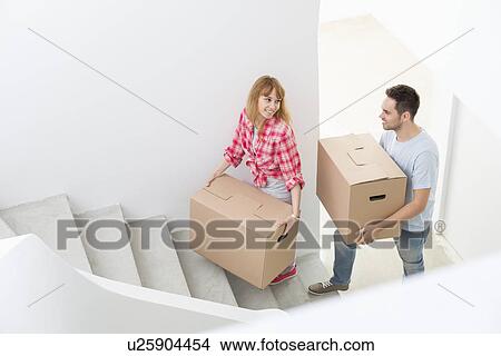 Happy couple carrying moving boxes up stairs in new house View Large Photo Image Picture - Happy couple carrying moving boxes up stairs in new house. Fotosearch