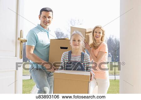 Stock Photograph - Happy family with cardboard boxes entering new home. Fotosearch