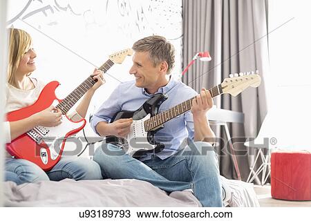 Happy father and daughter playing guitars at home View Large Photo Image Stock Image - Happy father and daughter playing guitars at home. Fotosearch