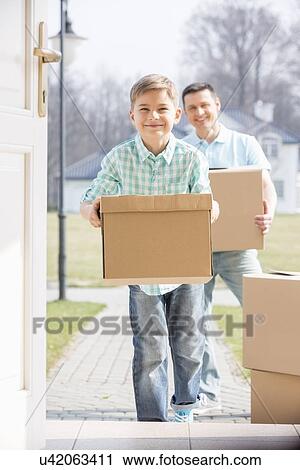 Stock Image - Happy father and son with cardboard boxes entering new home. Fotosearch