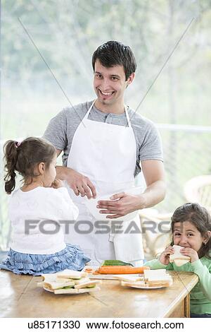 Happy father preparing food with little daughters at home View Large Photo Image Stock Image - Happy father preparing food with little daughters at home. Fotosearch