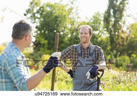 Happy gardeners talking at plant nursery View Large Photo Image Stock Photo - Happy gardeners talking at plant nursery. Fotosearch