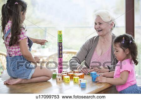 Happy grandmother and granddaughters playing with alphabet blocks at table View Large Photo Image Stock Image - Happy grandmother and granddaughters playing with alphabet blocks at table. Fotosearch