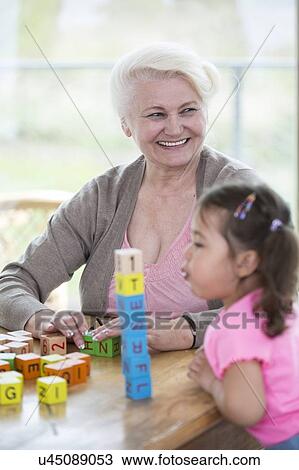 Happy grandmother looking away while granddaughter blowing stacked alphabet blocks in house View Large Photo Image Stock Image - Happy grandmother looking away while granddaughter blowing stacked alphabet blocks in house. Fotosearch