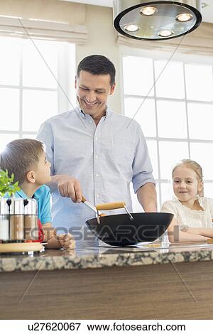 Happy man with children preparing food in kitchen View Large Photo Image Stock Photo - Happy man with children preparing food in kitchen. Fotosearch