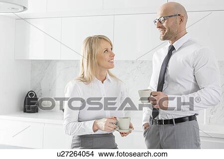 Happy mid adult business couple having coffee in kitchen View Large Photo Image Picture - Happy mid adult business couple having coffee in kitchen. Fotosearch