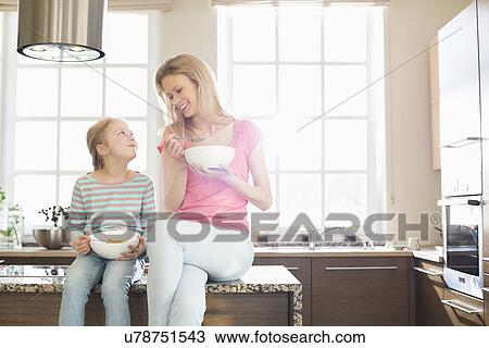 Happy mother and daughter having breakfast in kitchen View Large Photo Image Stock Image - Happy mother and daughter having breakfast in kitchen. Fotosearch
