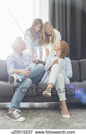 Stock Photo - Happy parents with daughters spending quality time in living room. Fotosearch