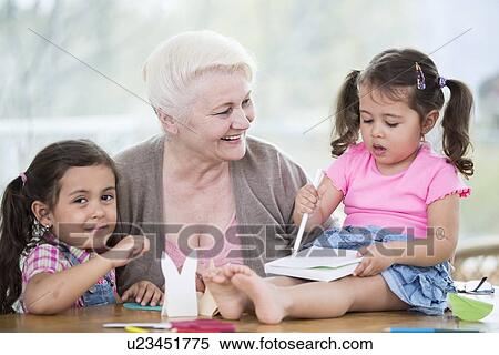 Stock Photography - Happy senior woman with granddaughters making handicraft at home. Fotosearch