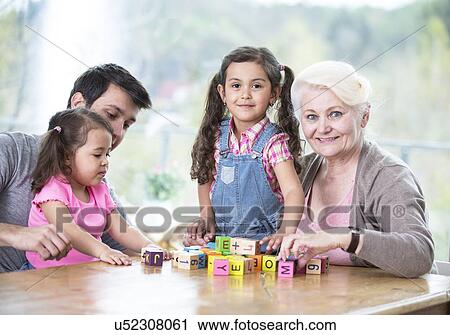 Stock Image - Happy three generation family playing with alphabet blocks at home. Fotosearch