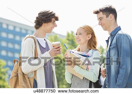Stock Image - Happy university students conversing at campus. Fotosearch