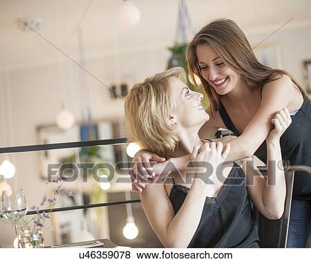 Happy woman embracing female friend in cafe View Large Photo Image Stock Photo - Happy woman embracing female friend in cafe. Fotosearch