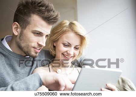 Stock Image - Happy young couple using digital tablet in cafe. Fotosearch
