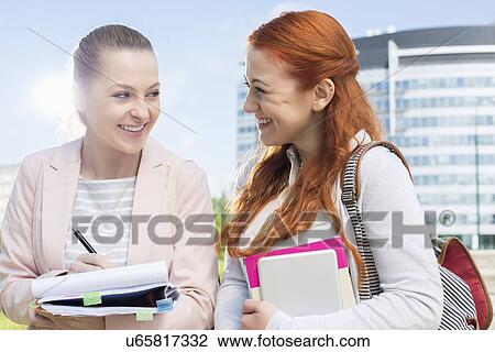 Stock Image - Happy young female college students studying outdoors. Fotosearch