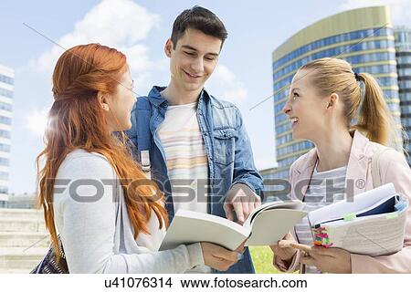 Picture - Happy young university students studying outdoors. Fotosearch