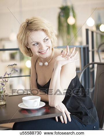 Happy young woman waving at restaurant table View Large Photo Image Stock Image - Happy young woman waving at restaurant table. Fotosearch