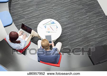 Stock Image - High angle view of business people using technologies in office. Fotosearch
