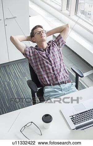 High angle view of businessman relaxing at desk in creative office View Large Photo Image Stock Image - High angle view of businessman relaxing at desk in creative office. Fotosearch