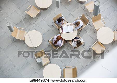 High angle view of businesswomen doing paperwork in office canteen View Large Photo Image Picture - High angle view of businesswomen doing paperwork in office canteen. Fotosearch