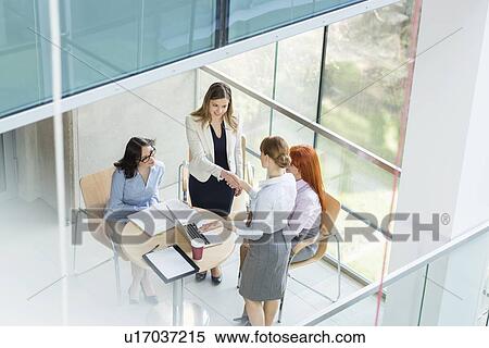 High angle view of businesswomen shaking hands at table in office View Large Photo Image Stock Photography - High angle view of businesswomen shaking hands at table in office. Fotosearch