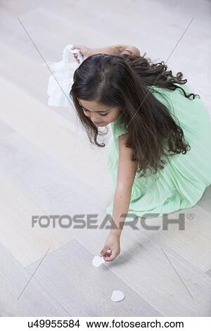 High angle view of girl picking up flower petals from floor at home View Large Photo Image Picture - High angle view of girl picking up flower petals from floor at home. Fotosearch