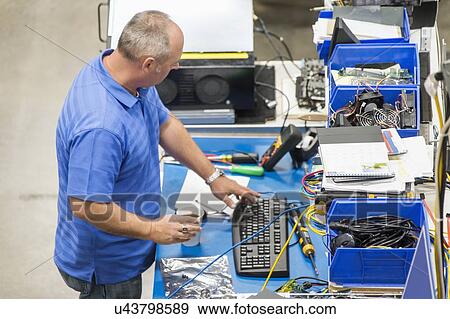 High angle view of mature male engineer working at desk in computer manufacturing industry View Large Photo Image Stock Photo - High angle view of mature male engineer working at desk in computer manufacturing industry. Fotosearch