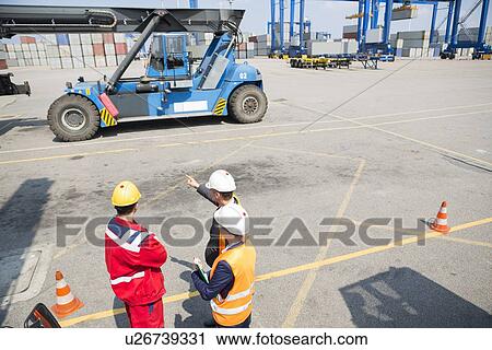 Stock Image - High angle view of workers discussing in shipping yard. Fotosearch