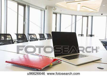 Laptop and files on conference table in creative office View Large Photo Image Stock Photograph - Laptop and files on conference table in creative office. Fotosearch