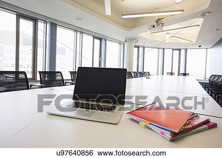Stock Photograph - Laptop and files on empty conference table in creative office. Fotosearch