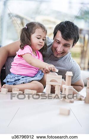 Little girl and father playing with wooden building blocks on floor View Large Photo Image Stock Image - Little girl and father playing with wooden building blocks on floor. Fotosearch