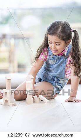 Stock Photo - Little girl building blocks while sitting on hardwood floor. Fotosearch