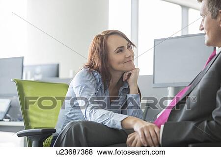 Loving business couple looking at each other in office View Large Photo Image Stock Photo - Loving business couple looking at each other in office. Fotosearch