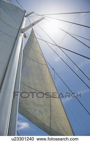 Stock Image - Low angle view of yacht sails and mast against sky. Fotosearch
