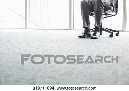 Low section of businessman sitting on office chair View Large Photo Image Picture - Low section of businessman sitting on office chair. Fotosearch