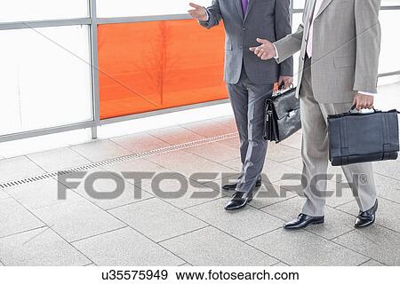 Low section of businessmen communicating while walking in railroad station View Large Photo Image Stock Photo - Low section of businessmen communicating while walking in railroad station. Fotosearch