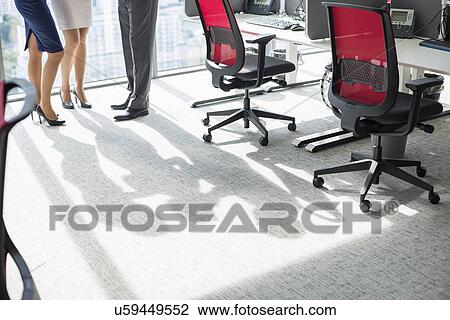 Stock Image - Low section of businesspeople standing in office. Fotosearch