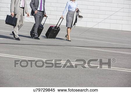 Low section of businesspeople with luggage walking on street View Large Photo Image Stock Photography - Low section of businesspeople with luggage walking on street. Fotosearch