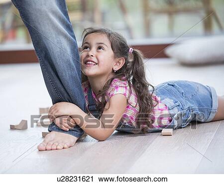 Stock Image - Low section of father dragging girl on hardwood floor. Fotosearch