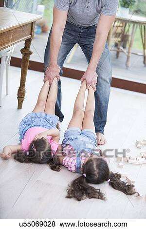 Low section of playful father dragging girls on hardwood floor View Large Photo Image Stock Photo - Low section of playful father dragging girls on hardwood floor. Fotosearch