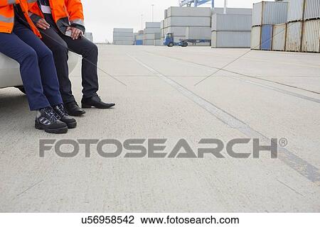 Low section of workers leaning on car in shipping yard View Large Photo Image Stock Image - Low section of workers leaning on car in shipping yard. Fotosearch