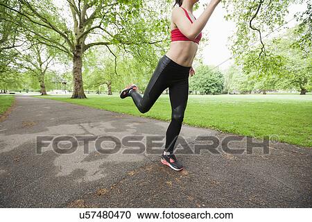 Stock Image - Low section of young woman jogging in park. Fotosearch