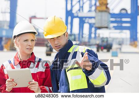 Male and female workers discussing in shipping yard View Large Photo Image Stock Photography - Male and female workers discussing in shipping yard. Fotosearch